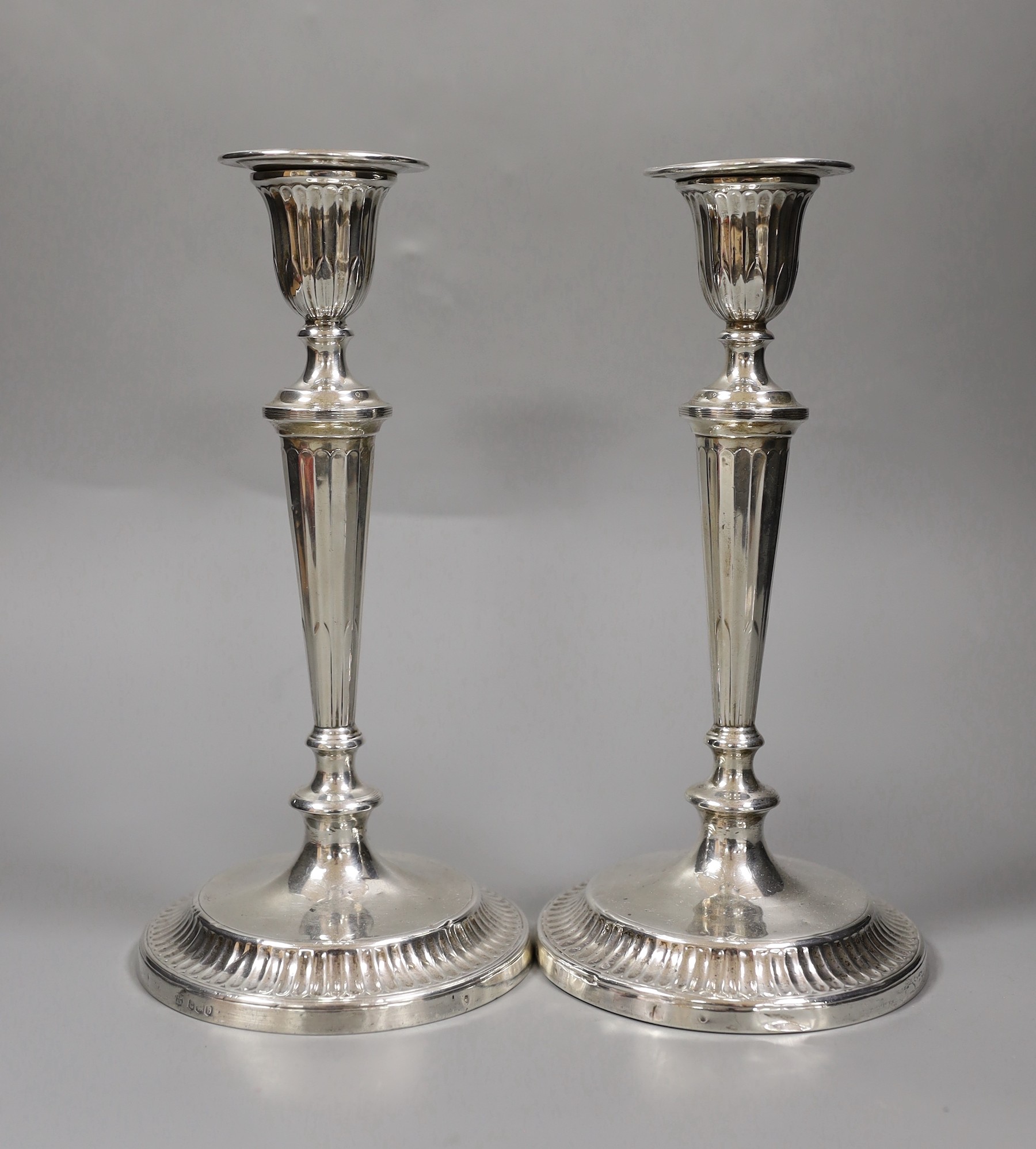 A pair of George V silver candlesticks, with panelled tapering stems, Thomas Bradbury & Sons, Sheffield, 1919, height 24cm.